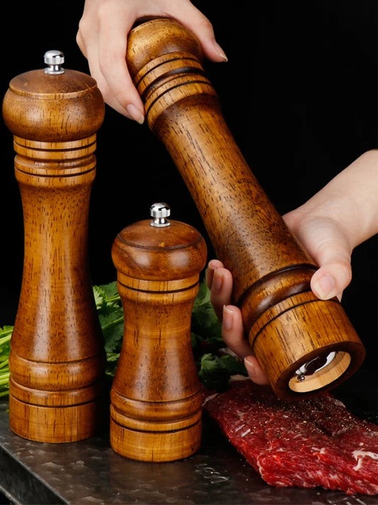 Two wooden salt and pepper grinders with metal tops, held by hands over food prep
