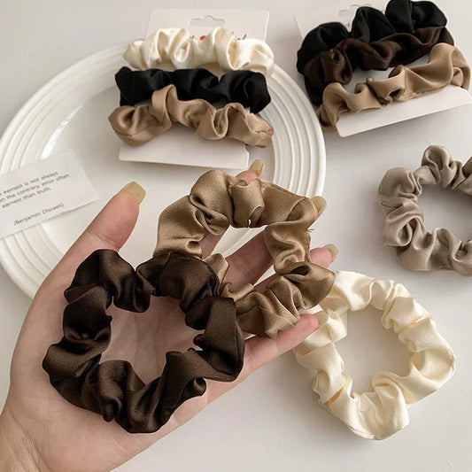 Assorted satin hair scrunchies in black, white, and brown ruffle style