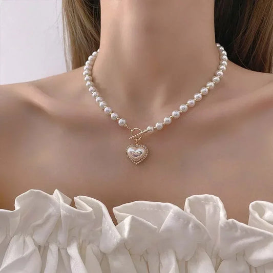 Faux pearl choker necklace with small heart charm pendant and clasp on curved neckline