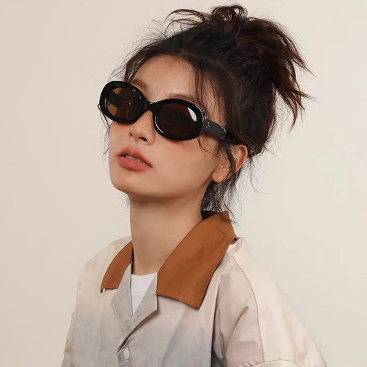 Black oval sunglasses with glossy frame and dark lenses, worn with an updo hairstyle
