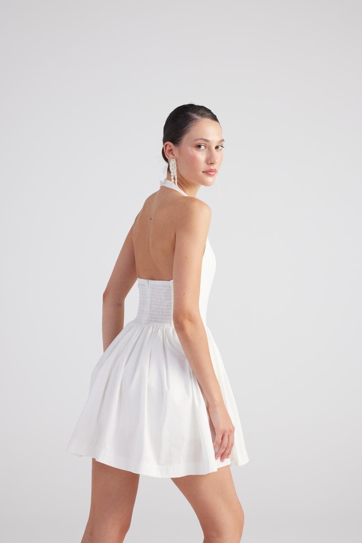 White pleated mini dress side view with thin straps and gathered waist