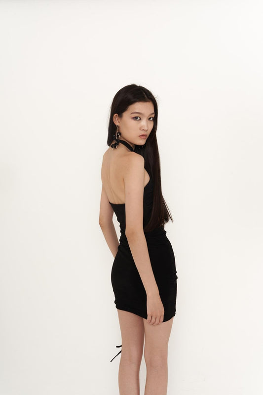 Black halter mini bodycon dress with open back, crisscross straps, and ruched sides