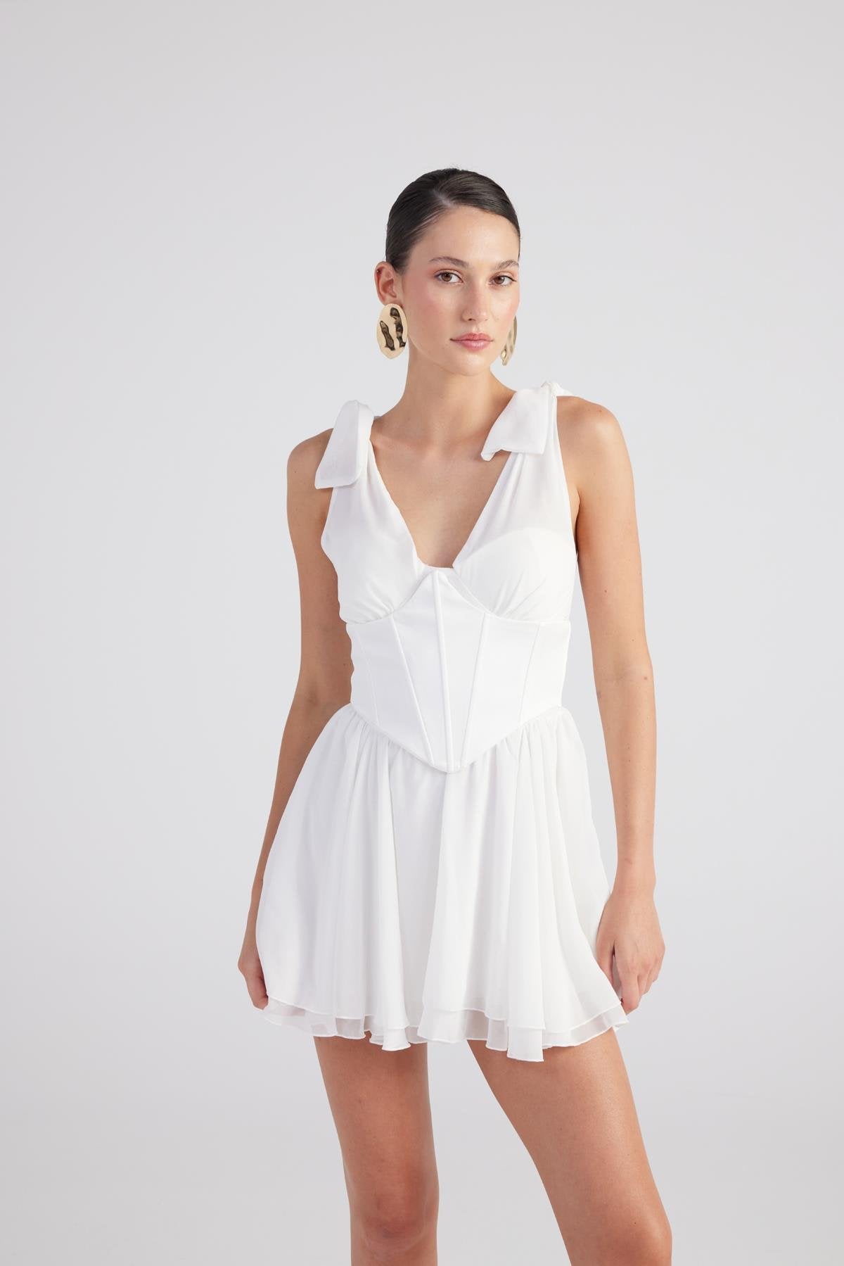 White ruched mini dress with V-neck, ruffled shoulders, and pleated skirt