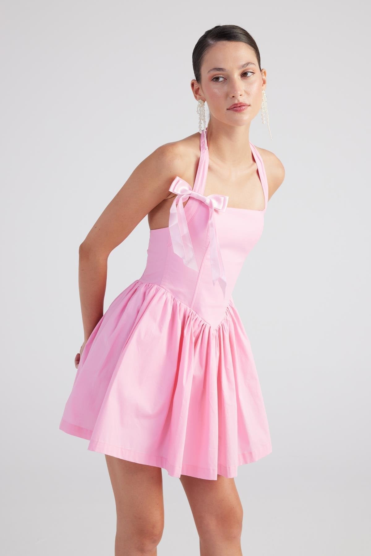 Pink halter mini dress close-up with bow detail and gathered pleated skirt