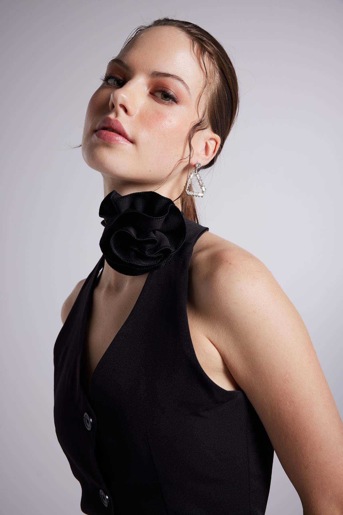 Black halter mini dress close-up of large shoulder rosette and button detail