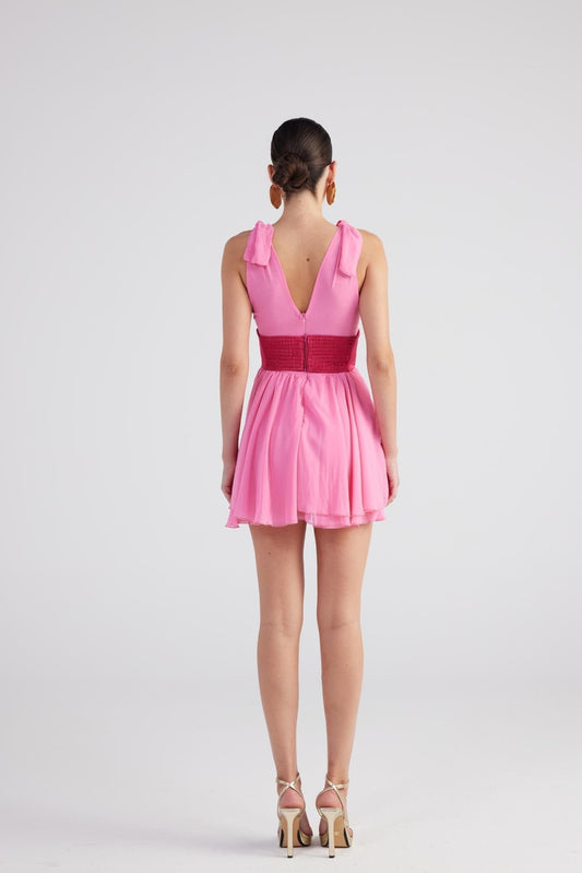 Pink sleeveless mini dress with V-back, ruched bodice, and pleated skirt