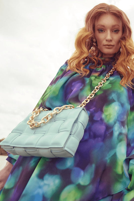 Light blue faux leather cross-body bag with gold chain strap and quilted woven front