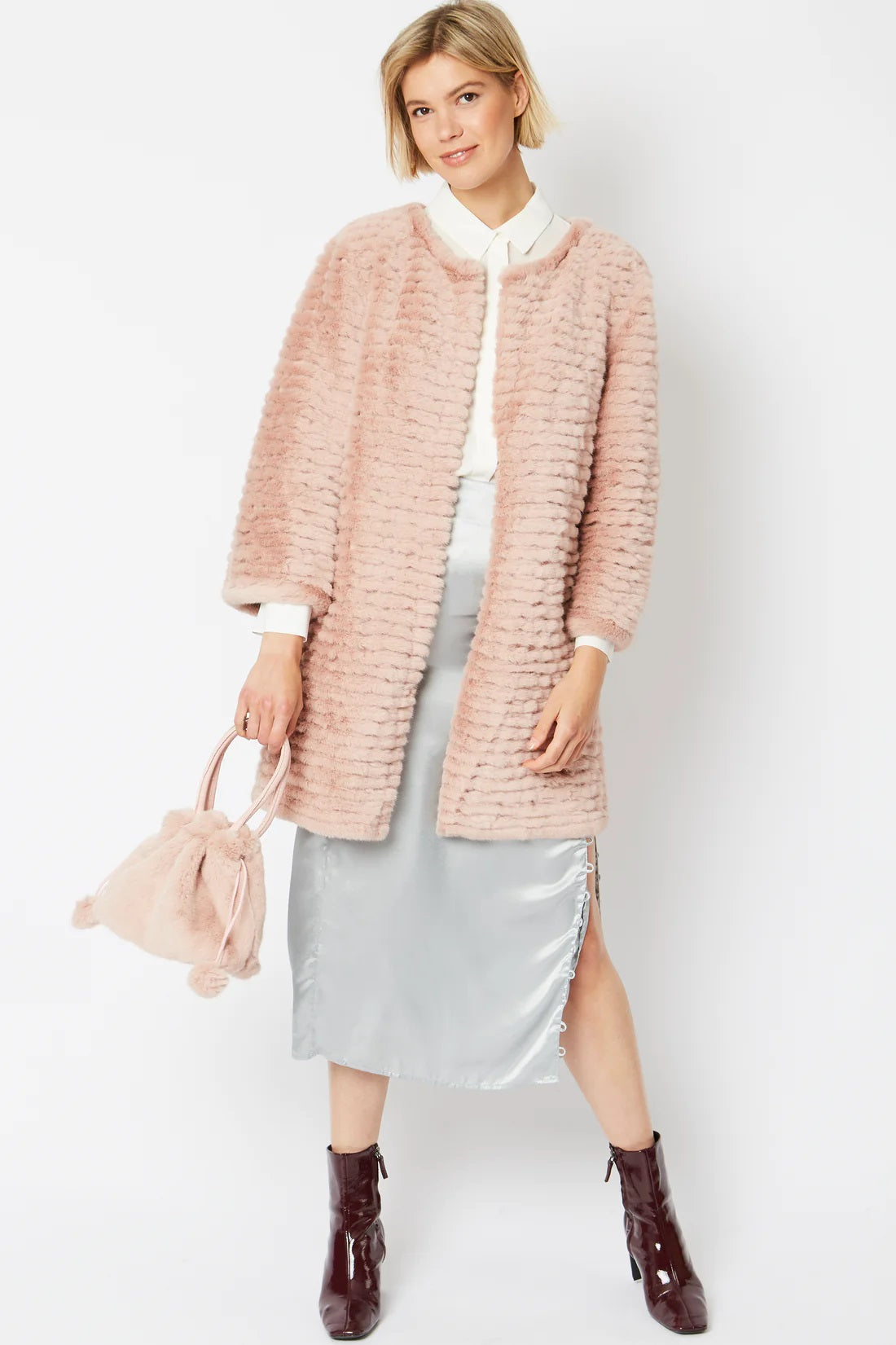 Pink faux fur bucket bag with pom-pom drawstring, shown being carried