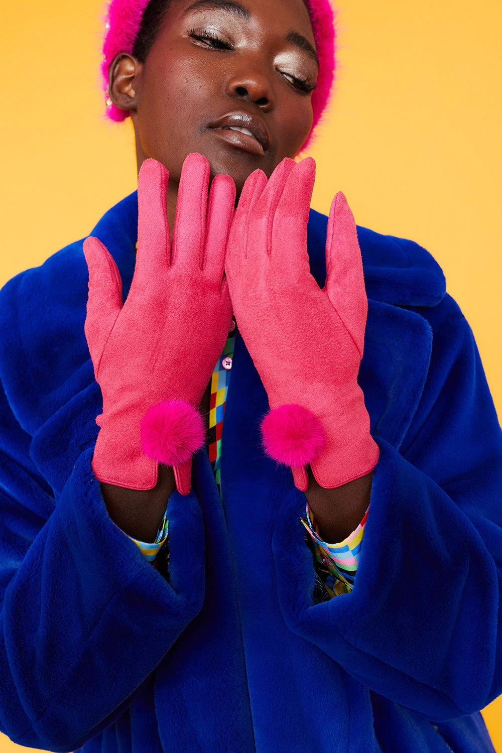 Pink faux suede gloves with faux fur pom at the wrist, hands held together