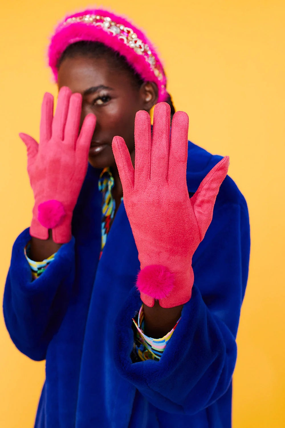 Pink faux suede gloves with faux fur pom at the wrist, hands raised