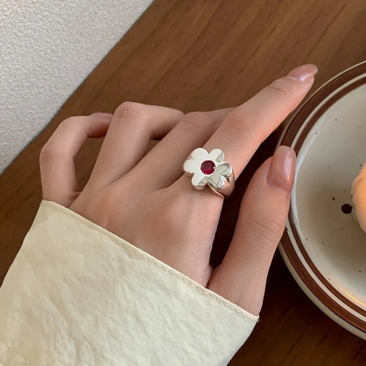 Adjustable open flower ring with white petals and a pink-red center stone on a hand