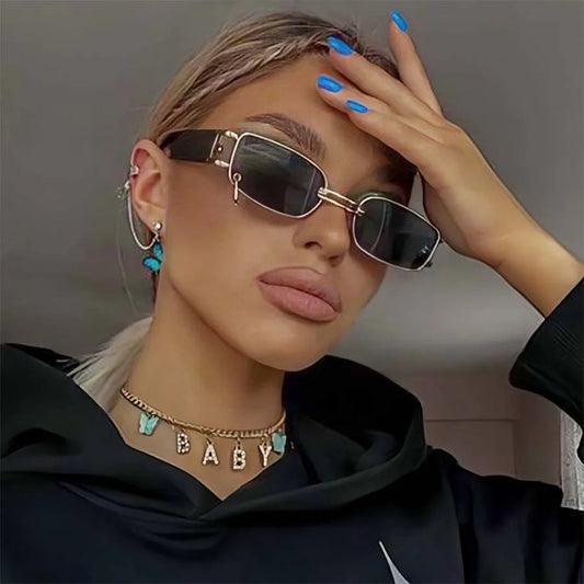 Square sunglasses on model, dark lenses, gold-tone frame with small mirror-style details
