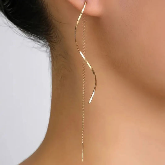 Gold-tone wavy long drop dangle earrings on ear, thin chain with spiral curve, stainless steel