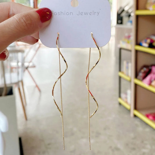 Gold-tone wavy long drop dangle earrings shown on display card, curved top and long chain