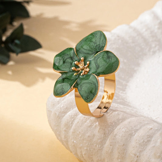Flower-shaped enamel ring with dark green petals and gold-tone center on display