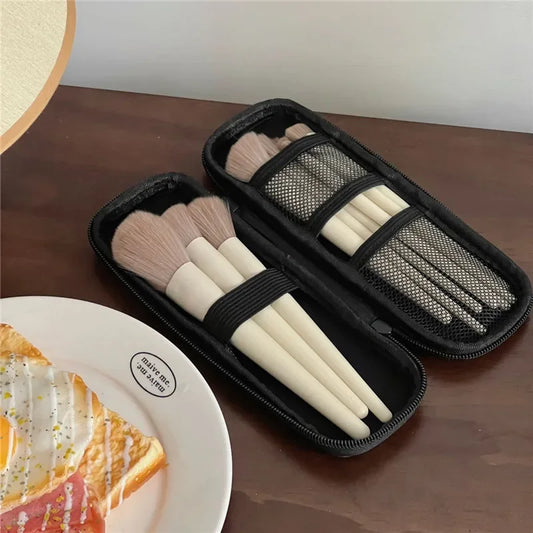 Black makeup brush case with two compartments, mesh windows, and zipper closure, open