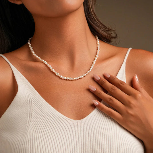 White baroque freshwater pearl necklace on neckline with sterling silver chain, close-up