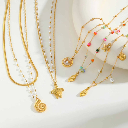 Gold tone charm necklace with seashell and starfish pendants plus white pearl beads