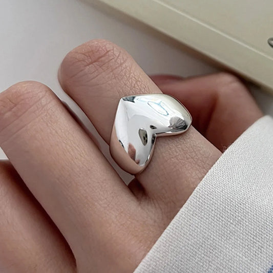 Polished 925 sterling silver heart ring with raised geometric cutout on finger