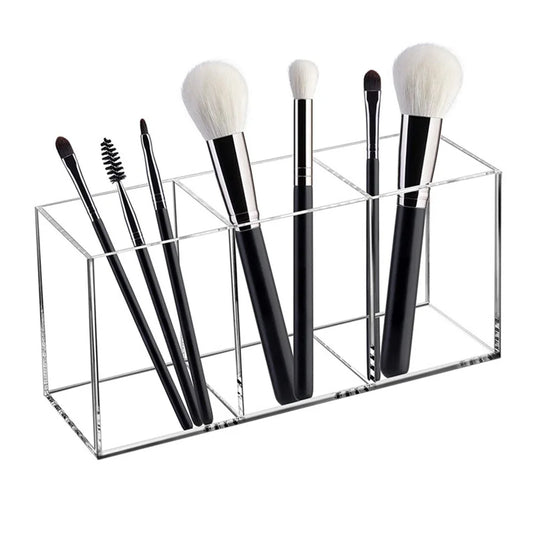 Clear acrylic makeup brush organizer with open top and multiple slots holding brushes