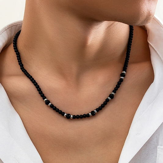 Black bead clavicle necklace with small dark crystal-toned spacers along the chain.