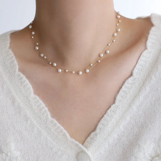 Gold-tone pearl chain necklace with small white pearls in a layered curve
