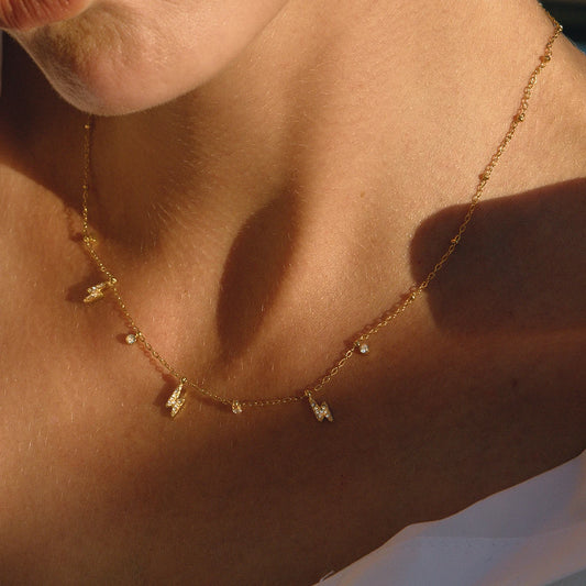 Gold-tone chain necklace with small rhinestone lightning pendant charms