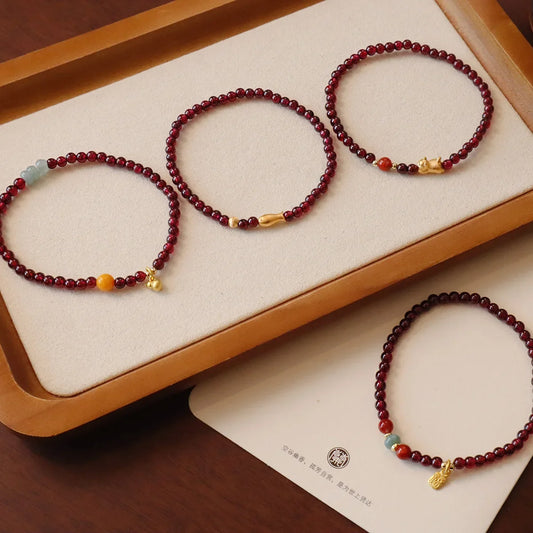 Set of four garnet beaded stack bracelets with gold charms and small gemstone beads
