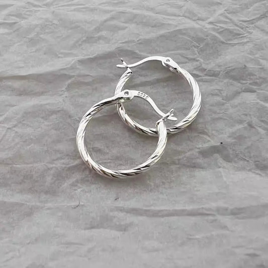 Silver twisted circle hoop earrings with hinged clasp and small sparkling details
