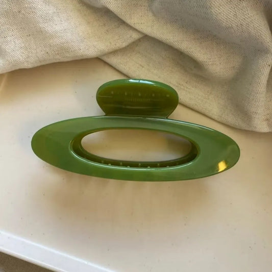 Green oval hair claw clip with hollow center and glossy finish.