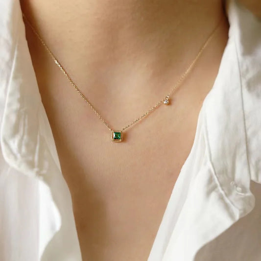 Gold-tone square pendant necklace with green crystal centerpiece and tiny round side charm