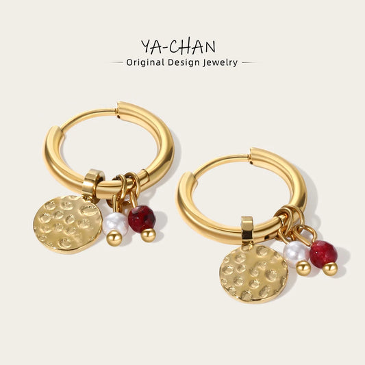 Gold hoop earrings with hammered round charms, red beads, and small pearl drops