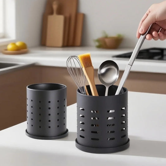 Perforated metal cutlery holder cylinders, black and silver, holding kitchen tools