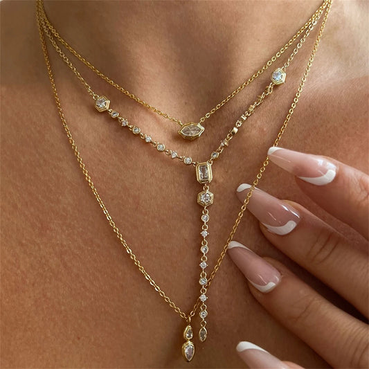 Gold-tone pendant necklace set with geometric zircon charms and a long dangling drop