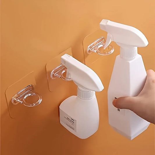 White adhesive wall hooks holding multiple trigger spray bottles on a wall