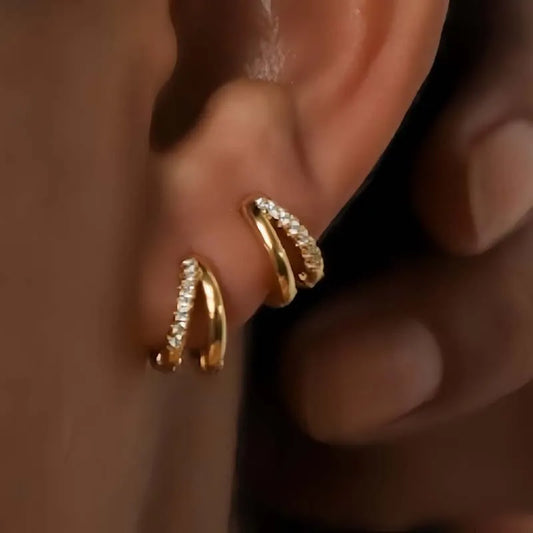 Gold huggie hoop earrings with double-row crystals, close-up on ear cartilage