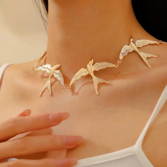 Gold swallow bird charm short necklace, layered chain design shown on shoulder