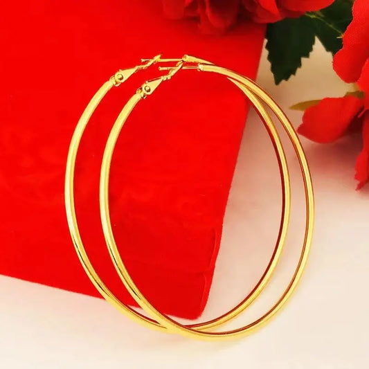 Pair of large round gold hoop earrings, close-up of smooth wire and hinge