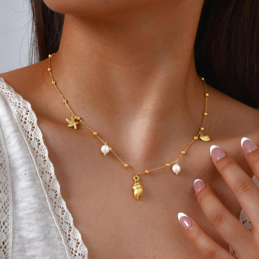 Gold tone beach necklace with starfish, shell charms, and small white pearl drops
