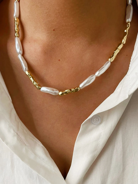 Close-up gold-tone necklace with irregular white baroque pearl links and gold caps