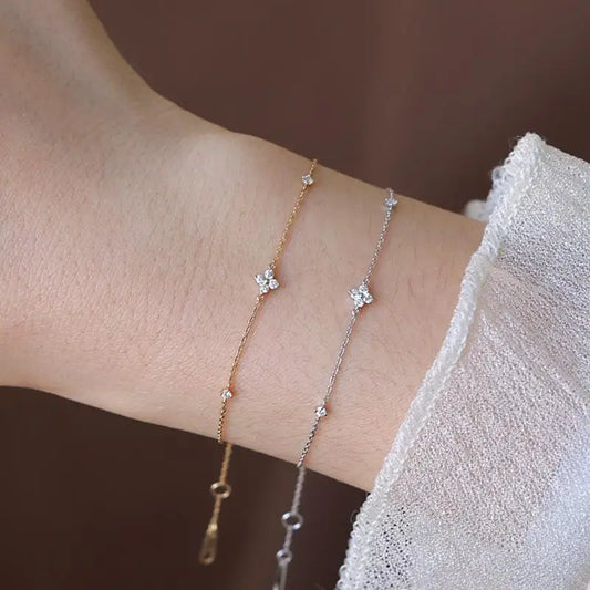 Two zirconia flower chain bracelets, gold and silver tones, on wrist with clasps