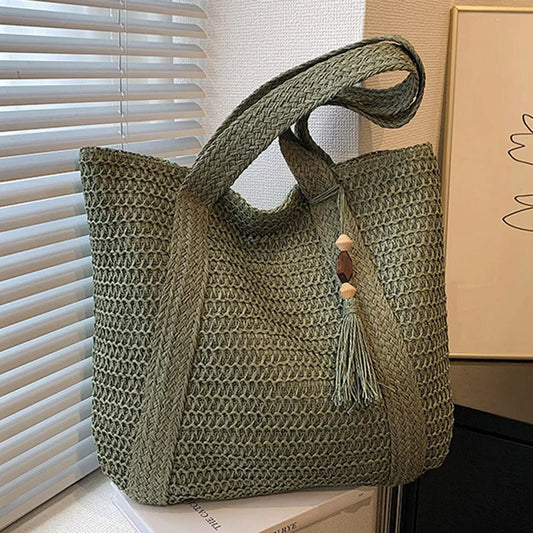 Olive green woven straw tote bag with long top handle and tassel charm