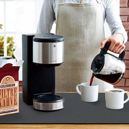Black dish drying mat on countertop under coffee appliances and cups