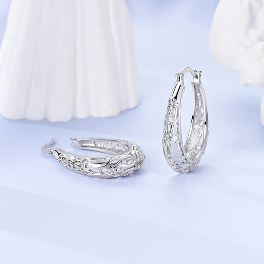 Sterling silver hoop earrings with ornate cutout details and small crystal stones