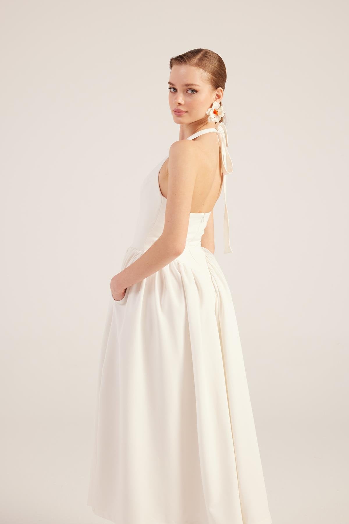 White sleeveless V-neck maxi dress with open back detail and gathered pleated skirt