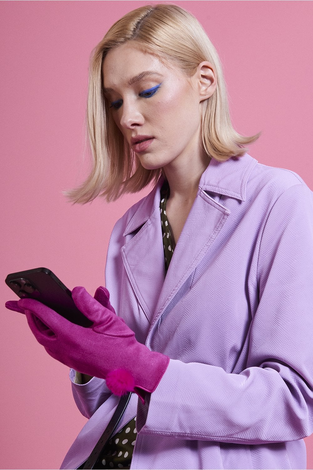 Pink faux suede gloves with faux fur pom at the wrist, side view on model hands