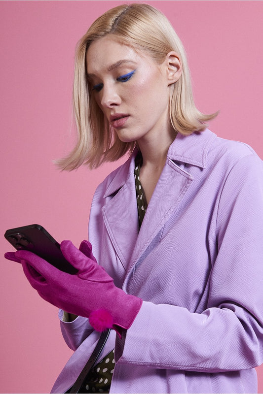 Pink faux suede gloves with faux fur pom at the wrist, side view on model hands