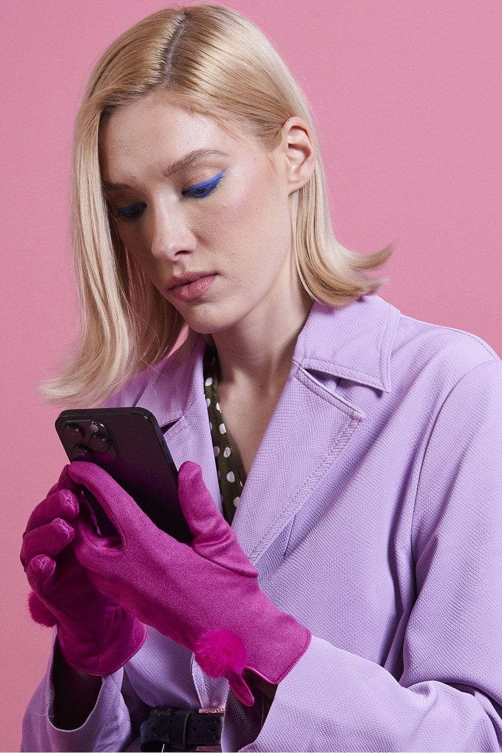 Pink faux suede gloves with faux fur pom at the wrist, worn in hand pose