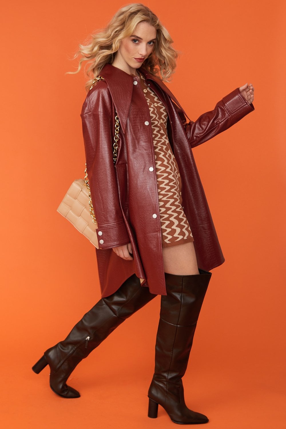 Deep red oversized faux leather trench coat with exaggerated collar and buttoned front